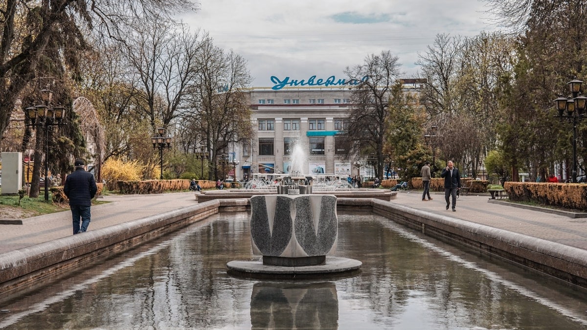 a fountain in a park with people walking around