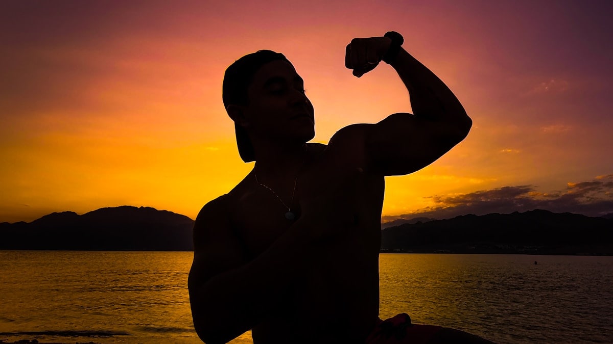 a man holding a bottle of water in front of a sunset
